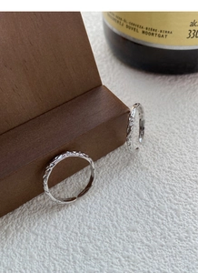 Detailed macro view of 999 sterling silver rings with hammered texture on a wooden stand