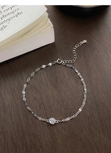 Macro detail of S925 sterling silver chain with sparkling round zircon on wooden desk