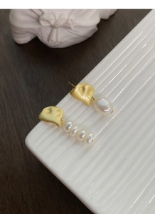 Macro detail of asymmetric S925 silver earrings with baroque pearls and matte gold finish