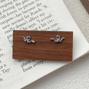 Elegant S925 silver snake stud earrings featuring colorful zircon stones on a wooden stand