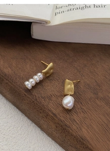 Detail of asymmetric S925 silver pearl earrings on wood with baroque freshwater pearls