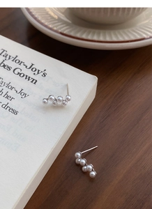 Détail de boucles d'oreilles en perles de raisin en argent S925 sur un livre d'esthétique