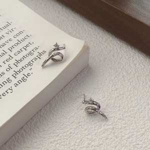 Minimalist S925 silver snake-shaped stud earrings with tiny diamonds on artistic background
