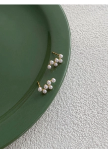 Vue détaillée des boucles d'oreilles S925 en argent avec cinq perles blanches et base dorée