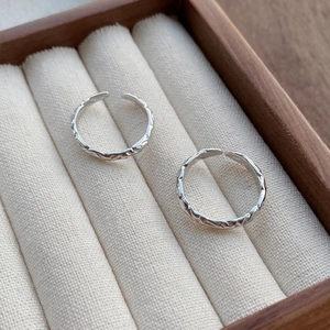 Pair of adjustable 999 sterling silver rings with hammered candy paper texture on wood