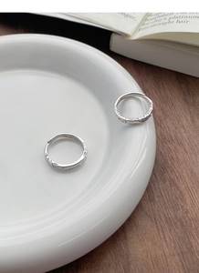 Detail of hammer-textured S999 sterling silver adjustable couple rings on white ceramic tray