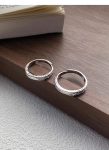 Detailed macro view of S999 sterling silver glacier textured open rings on wooden stand