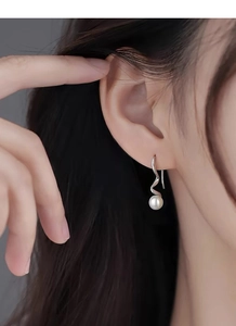 Close-up of elegant S925 silver wave hook earrings with round freshwater pearls on model