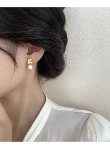 Close-up of asymmetrical S925 silver earrings with baroque pearls and gold metal on a model