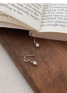 Detailed macro shot of S925 sterling silver spiral hook earrings with white freshwater pearls
