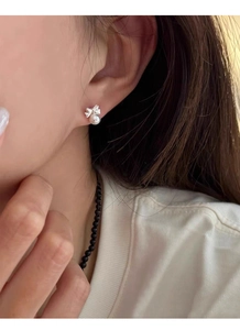 Close-up of butterfly pearl sterling silver stud earrings worn on a woman ear