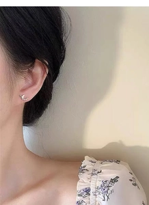 Gros plan d'une puce d'oreille papillon dorée délicate portée sur le lobe d'une oreille