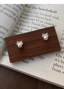 Detailed view of 999 sterling silver butterfly bow earrings with round white pearls