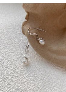 Macro detail of silver spiral drop earrings featuring round white freshwater pearls