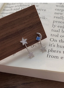 Macro detail of asymmetric S925 silver star and moon earrings with blue zircon