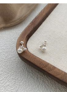 Macro shot of butterfly bow sterling silver earrings with round white pearls on display