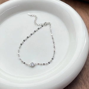 S925 sterling silver chain bracelet with a sparkling round zircon stone in a white ceramic dish