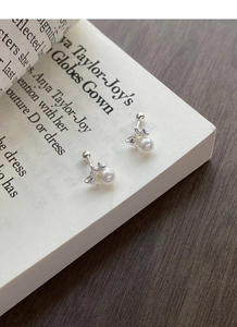 Detailed close-up of butterfly pearl screw back earrings on a vintage book page