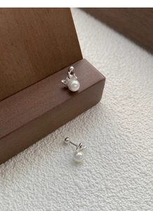 Detail of silver butterfly pearl earrings with secure screw back design on wood stand