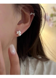 Detailed view of silver butterfly stud with pearl drop and matching ear cuff on model