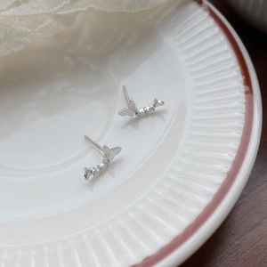 Boucles d'oreilles papillon en argent 999 avec zircons brillants sur assiette blanche