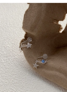 Close-up of S925 silver star and moon asymmetric ear clips with blue gemstone insets