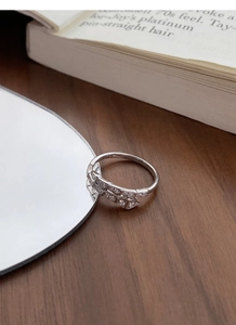 Detail view of S925 sterling silver snake-shaped ring with pavé diamonds on a wooden desk