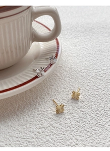 Close-up of S999 silver and gold four-leaf clover stud earrings with textured flower patterns