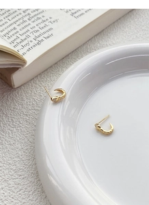 Detailed view of S925 silver gold-plated snake earrings with sparkling zircons on white ceramic