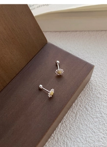Detaillierte Makroansicht der S925 Gänseblümchen-Ohrstecker auf Holz mit stoffigem Hintergrund