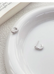 Macro shot of S925 sterling silver snake stud earrings with zircons on white ceramics