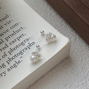 999 Sterling silver butterfly pearl stud earrings with screw back on a vintage book