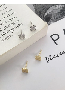 Macro shot of silver four-leaf clover stud earrings showing fine radiating textures