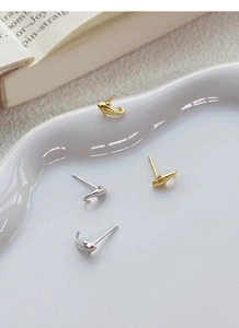 Detailansicht von Delphin-Silberohrringen in Gold und Silber auf einer Keramikplatte