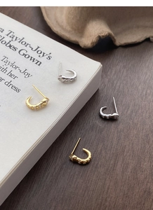 Detail of snake earrings with micro-inlaid rhinestones on a vintage book surface