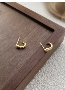 Close-up of S925 sterling silver hallmark on gold-plated snake earrings with sparkling zircons