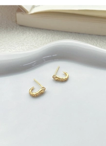 Macro view of gold S925 silver snake stud earrings with shimmering cubic zirconia