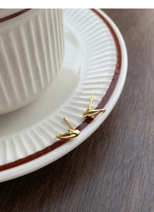 Nahaufnahme der goldenen Delfin-Ohrstecker auf einer Vintage-Keramikplatte aus Stein