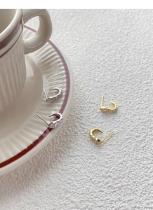 Macro detail of S925 silver snake stud earrings with zircons in gold and silver finish
