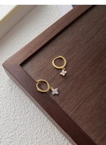 Détail de boucles d'oreilles fleur en argent S925 doré avec zircon blanc sur bois