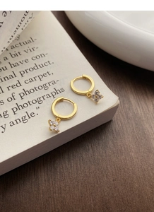 Détail des boucles d'oreilles créoles dorées en argent S925 avec pendentif trèfle