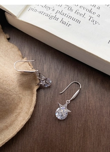 Détail de boucles d'oreilles étoile en argent S925 avec zircons sur bois rustique