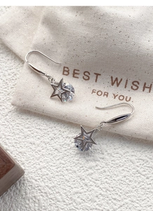 Détail de boucles d'oreilles étoile en argent S925 avec zirconiums sur tissu de lin