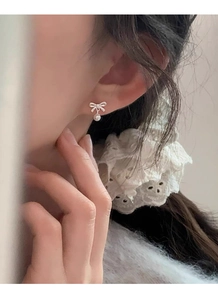 Close-up of elegant S999 sterling silver bow knot pearl stud earrings worn by a model