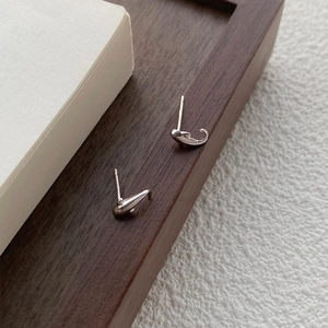 Minimalistische S999 Sterling Silber Delfin Ohrstecker auf Holz und weißem Hintergrund