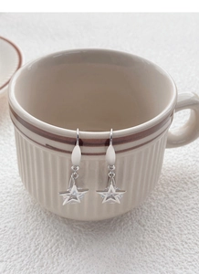 Gros plan de boucles d'oreilles étoile en argent S925 sur le bord d'une tasse