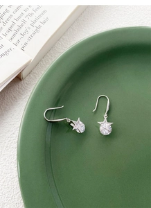 Détail de boucles d'oreilles pendantes en argent S925 avec étoiles sur plat vert