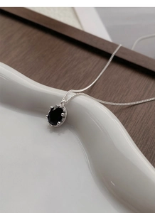 Macro view of minimalist 925 sterling silver necklace with black oval zircon pendant