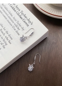 Détail de boucles d'oreilles étoile en argent S925 avec zircons brillants sur un livre