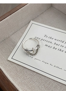 Close-up of S925 sterling silver vintage cross ring with chain on a textured backdrop